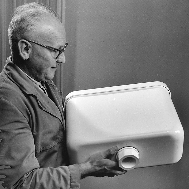 Ein technischer Berater präsentiert eines der frühen Spülkastenmodelle aus PVC. Die Spülkästen komplett aus Kunststoff waren eine Weltneuheit in den 1950er-Jahren.